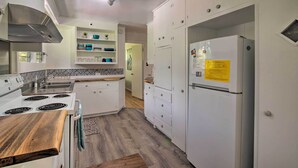 A modern kitchen with white cabinets, a stainless steel range hood, a built-in oven, a refrigerator, and a wooden countertop. - Hilo Apartment: Ocean Views on the Hamakua Coast! (Hilo)