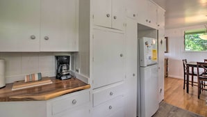 A kitchen with white cabinets, a coffee maker, and a refrigerator. - Hilo Apartment: Ocean Views on the Hamakua Coast! (Hilo)