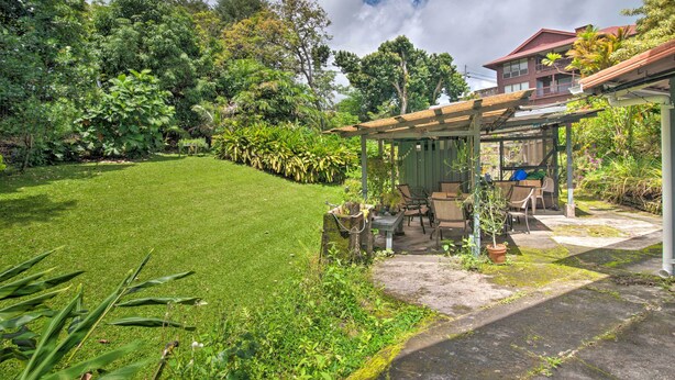 A well-maintained garden with a patio area, outdoor furniture, and a house in the background. - Hilo Apartment: Ocean Views on the Hamakua Coast! (Hilo)
