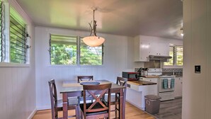 A kitchen with white cabinets, a wooden dining table, and chairs. - Hilo Apartment: Ocean Views on the Hamakua Coast! (Hilo)