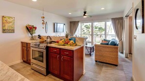 Una cocina moderna con una isla central, electrodomésticos de acero inoxidable y una zona de comedor con sofá y mesa de mimbre.