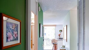 A hallway with green walls, a patterned rug, and a dining area with chairs and a table. - Oceanview Kailua-kona Condo With Private Balcony! (Kailua-Kona)
