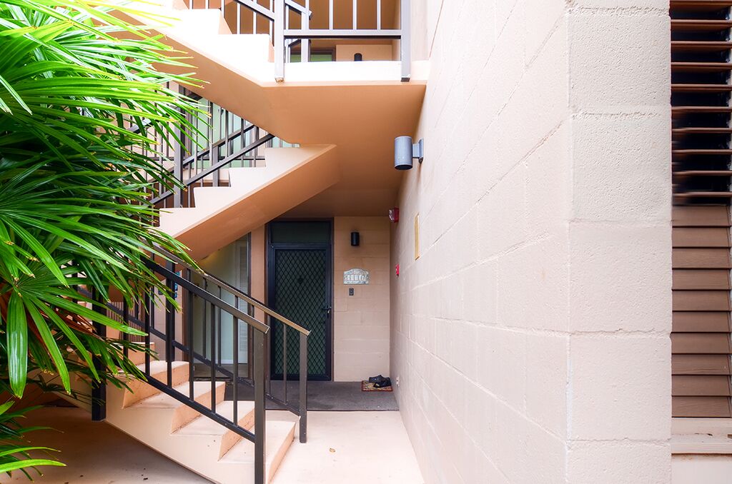 A multi-level residential building with a staircase, a door, and a small outdoor area with a plant.