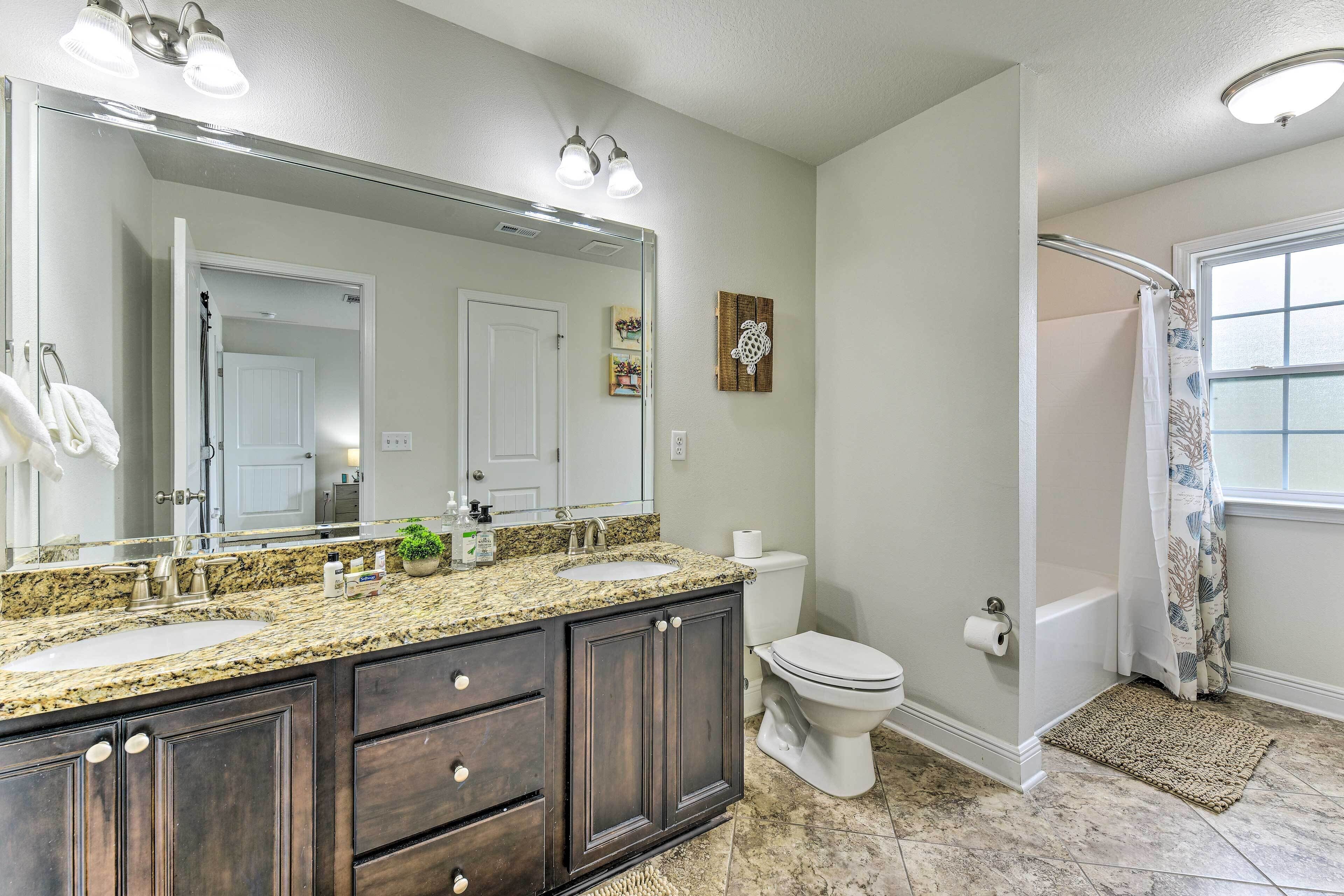 A bathroom with a double sink vanity, a toilet, a shower with a glass door, and a large mirror.