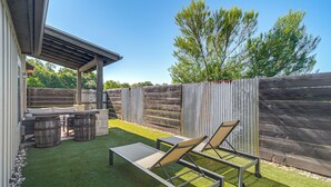 Un patio con una pérgola, mobiliario exterior y una cerca de madera.