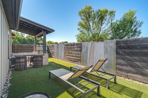 Une terrasse dotée d’une pergola, d’un espace salon extérieur et d’une clôture en bois.