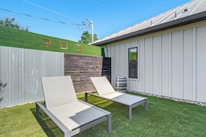 A patio with two lounge chairs, a wooden fence, and a building with the number '303' on it.