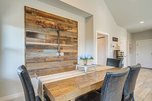 A dining area with a wooden table and chairs, a rustic wall art piece, and a small plant on a side table.