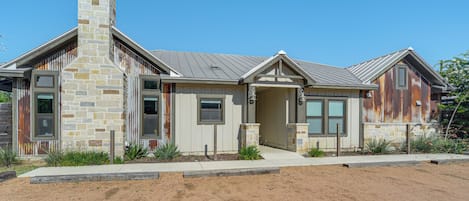 A modern house with a stone chimney, multiple windows, and a well-maintained lawn.