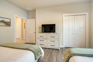 A bedroom with two beds, a TV on a dresser, and a closet.