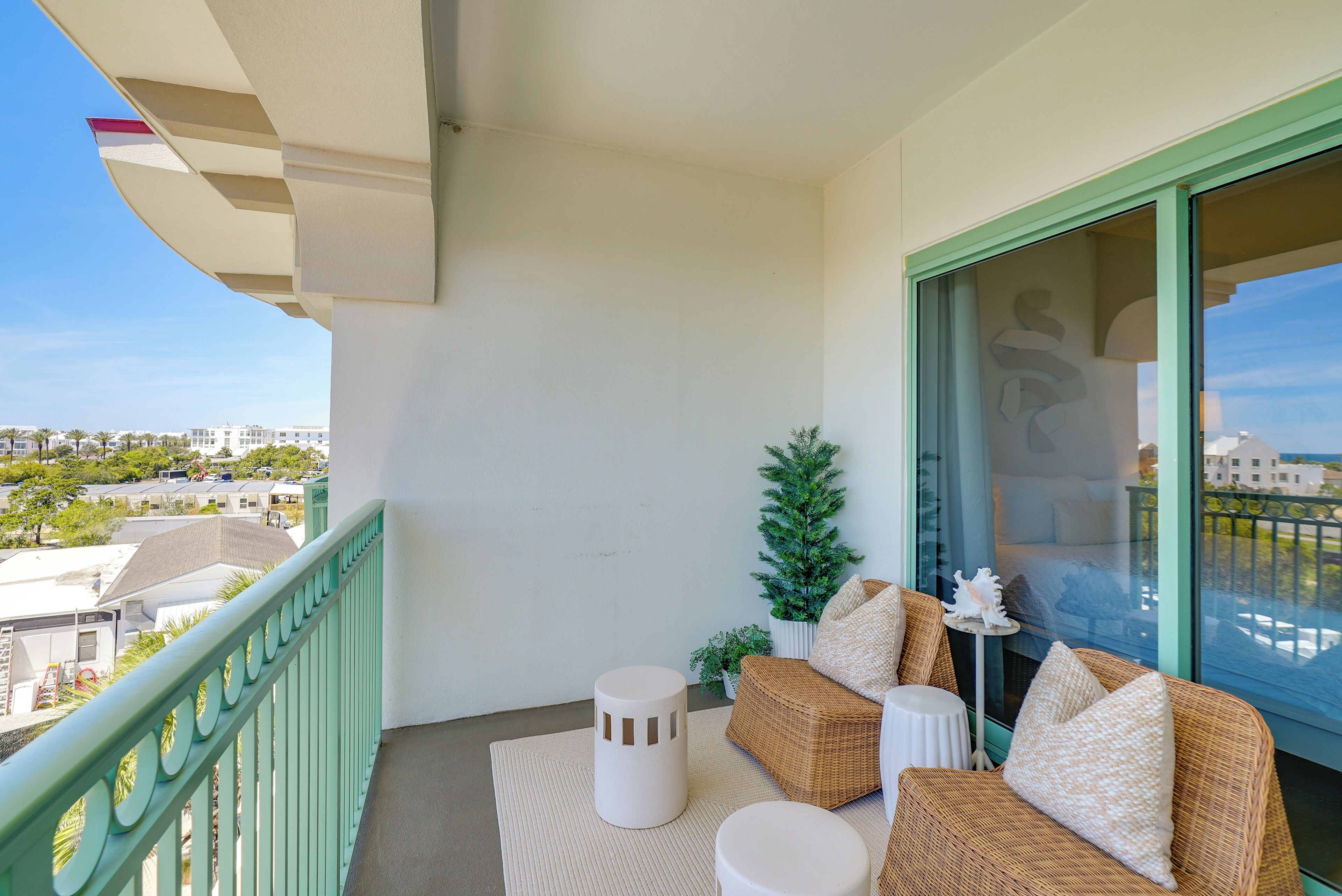 A balcony with wicker furniture, a small potted plant, and a view of the cityscape.