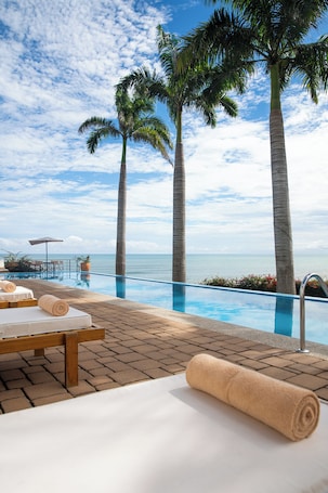 Una piscina al aire libre, sombrillas, sillones reclinables de piscina