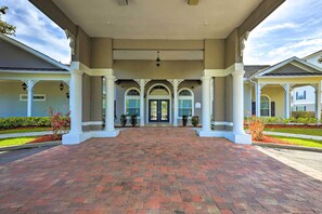 A covered entrance with a brick pathway leading to a double door, flanked by columns and potted plants. - Sun-soaked Kissimmee Gem w/ Resort Amenities! (Kissimmee)