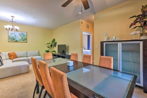 A living room with a glass-top dining table, a sofa, and a television. - Sun-soaked Kissimmee Gem w/ Resort Amenities! (Kissimmee)