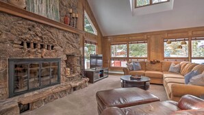 A spacious living room with a stone fireplace, a television, a large sofa, and a stone wall. - 2 Mi to Slopes! Hot Tub Hideaway in Breckenridge (Breckenridge)
