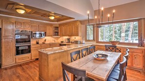 A spacious kitchen with wooden cabinets, a large island, and a dining area with a table and chairs.