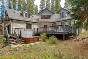 Une cabane à deux étages dotée d’un jacuzzi, d’une terrasse en bois et d’un escalier menant à un balcon.