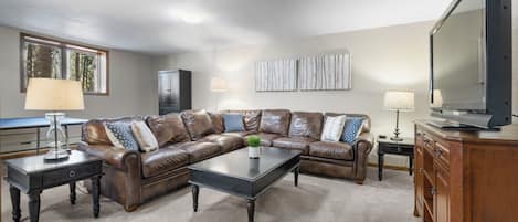 A living room with a L-shaped sectional sofa, a coffee table, a television, and a cabinet.