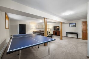 Una habitació amb taula de ping-pong, televisió, sofà i armari.