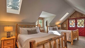 A bedroom with two wooden beds, a skylight, and a red door.