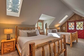 A bedroom with two wooden beds, a skylight, and a red door.