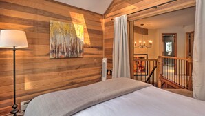 A wooden-paneled bedroom with a bed, a standing lamp, a painting, and a view of a staircase and another room. - 2 Mi to Slopes! Hot Tub Hideaway in Breckenridge (Breckenridge)