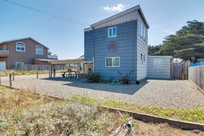 A two-story building with a blue exterior and a red wheel symbol on the side. - Bandon Home w/ Patio, Steps to South Jetty Park (Bandon)