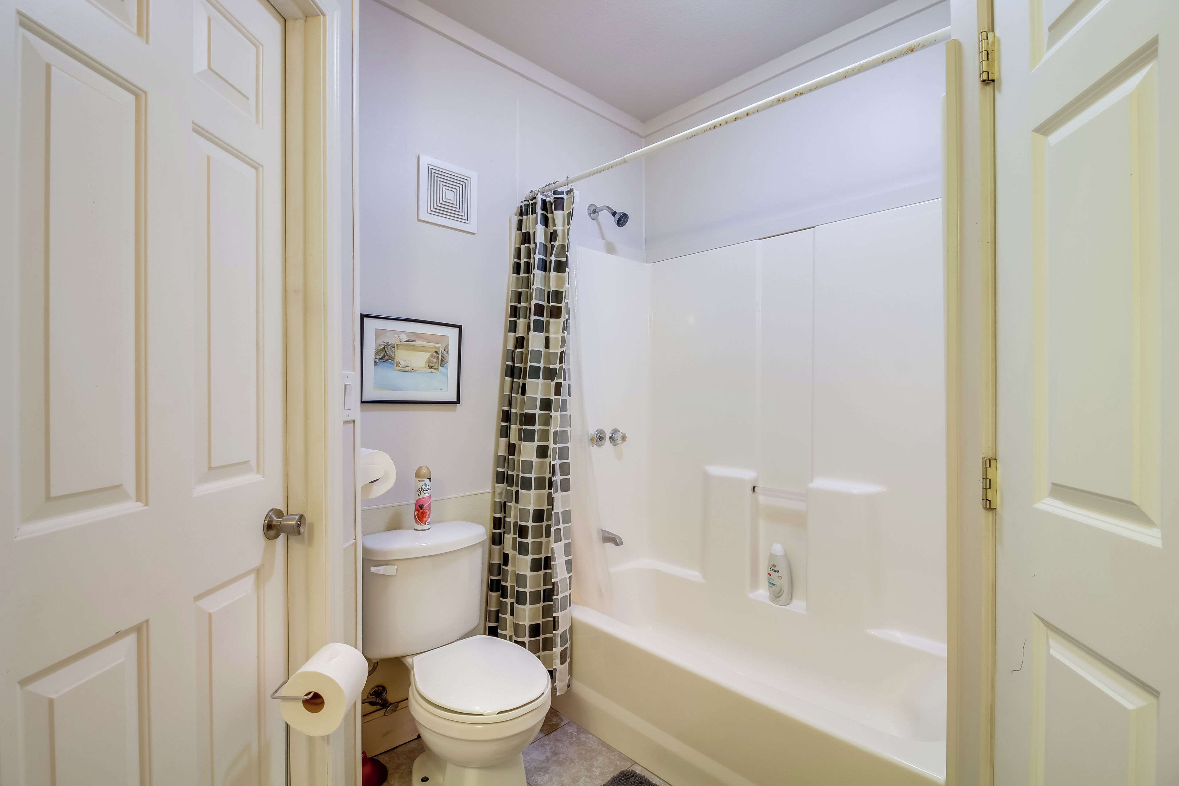 Une salle de bain comprenant des toilettes, une douche avec un rideau à motifs et une baignoire.