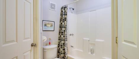 Une salle de bain comprenant des toilettes, une douche avec un rideau à motifs et une baignoire.