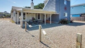 Une maison à deux étages avec un porche abrité, une cheminée et un petit jardin.