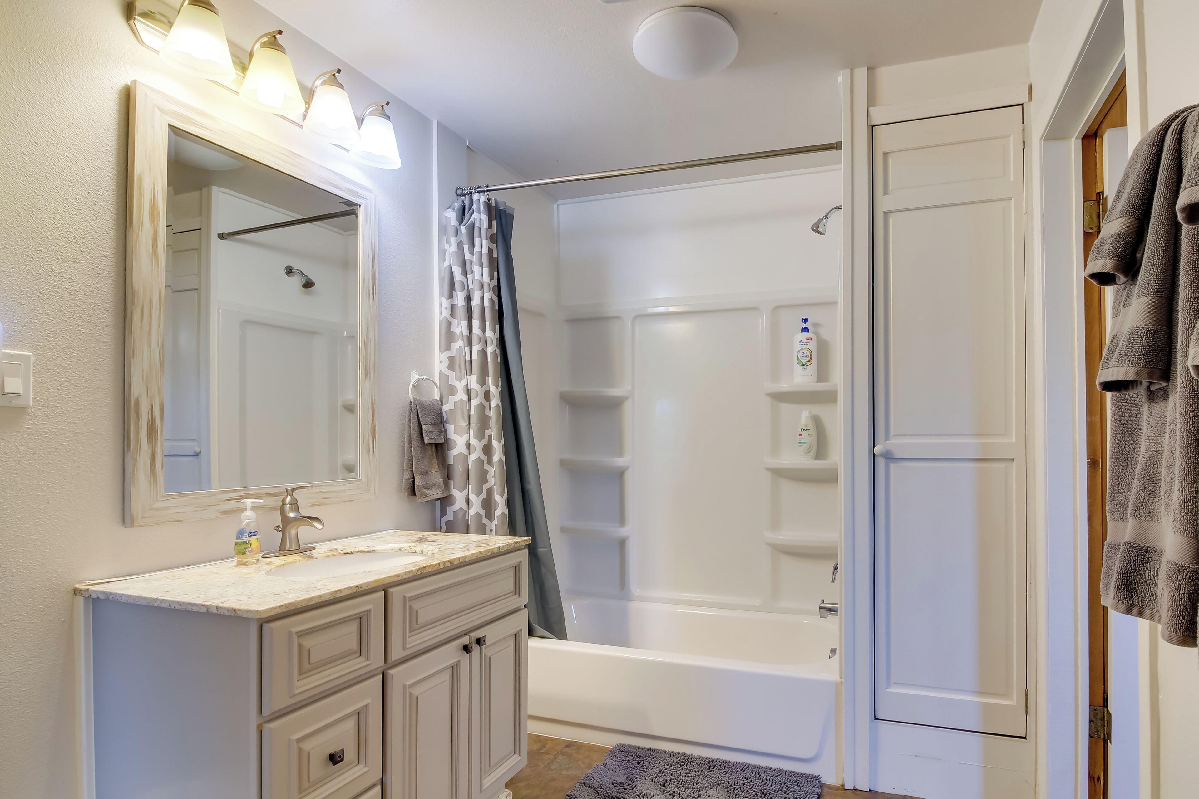 A bathroom with a vanity, mirror, shower, and a towel rack.