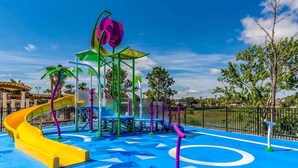 Une aire de jeux avec un toboggan jaune, une structure d’escalade et un espace de jeux bleu orné de motifs géométriques.