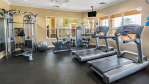 Une salle de sport équipée de tapis de course, d’appareils de musculation et d’un rameur.