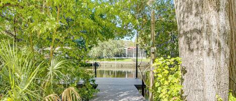 A pathway leading to a body of water, surrounded by lush greenery and trees.