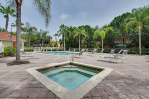 Uma área de piscina com espreguiçadeiras e palmeiras.