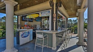 An outdoor bar area with a Bud Light refrigerator, a menu board, and bar stools. - Near Disney & Epic Universe: Home w/ Resort Perks (Kissimmee)