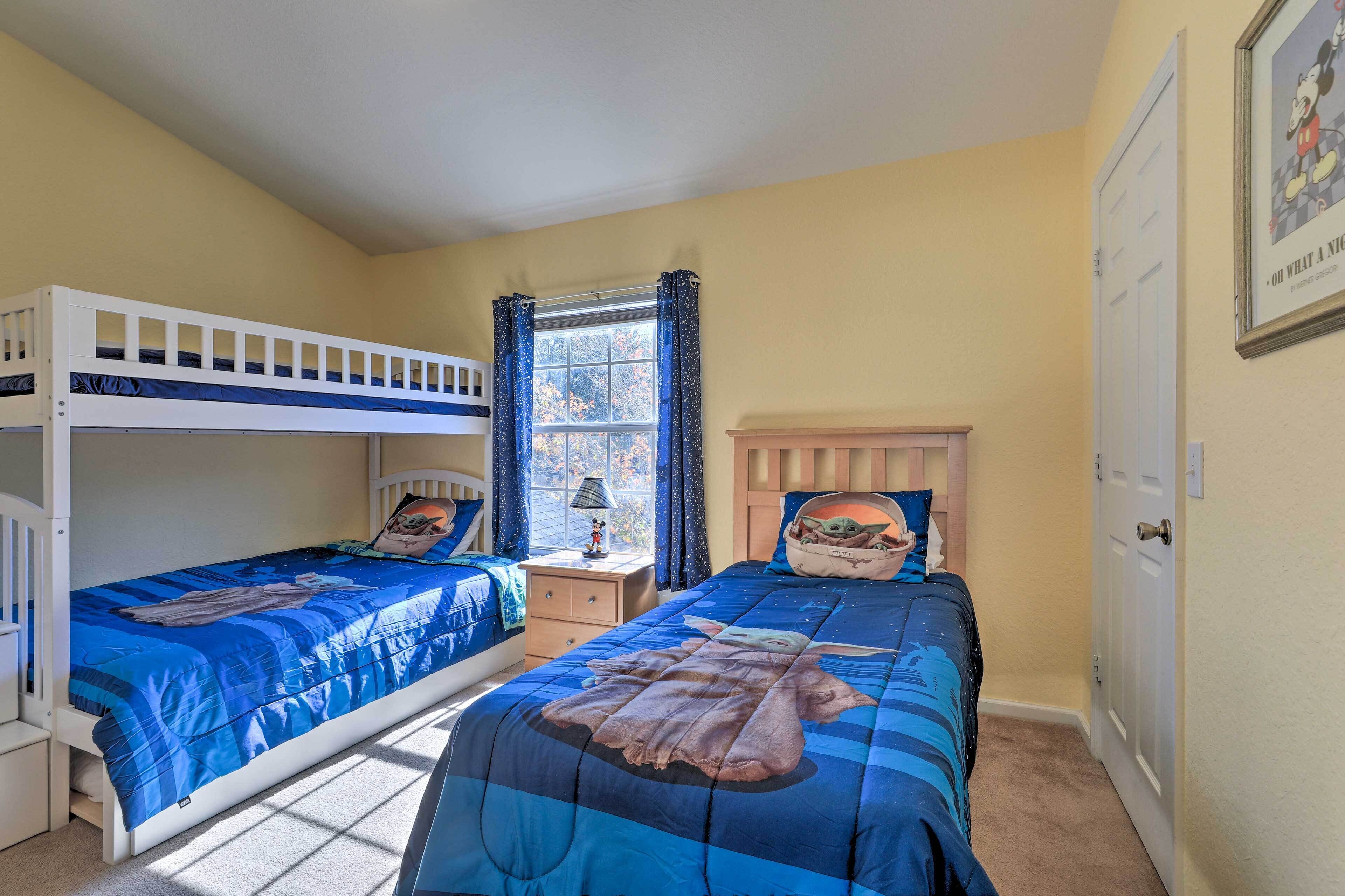 A bedroom with two bunk beds, a nightstand, a window with curtains, and a door.