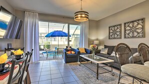 A modern living room with a dining area, large windows, and a pool view. - Private Cocktail Pool: Kissimmee Resort Retreat! (Kissimmee)
