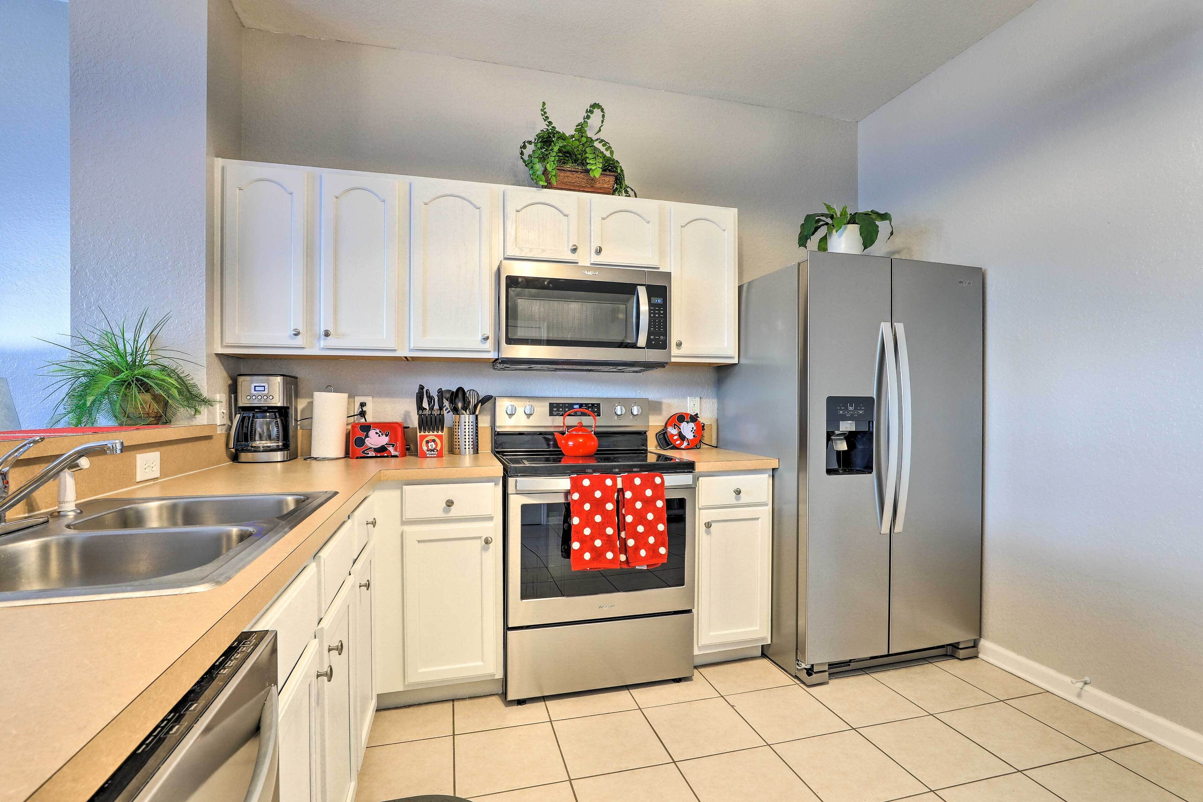 A modern kitchen with white cabinets, stainless steel appliances, and a tiled floor.