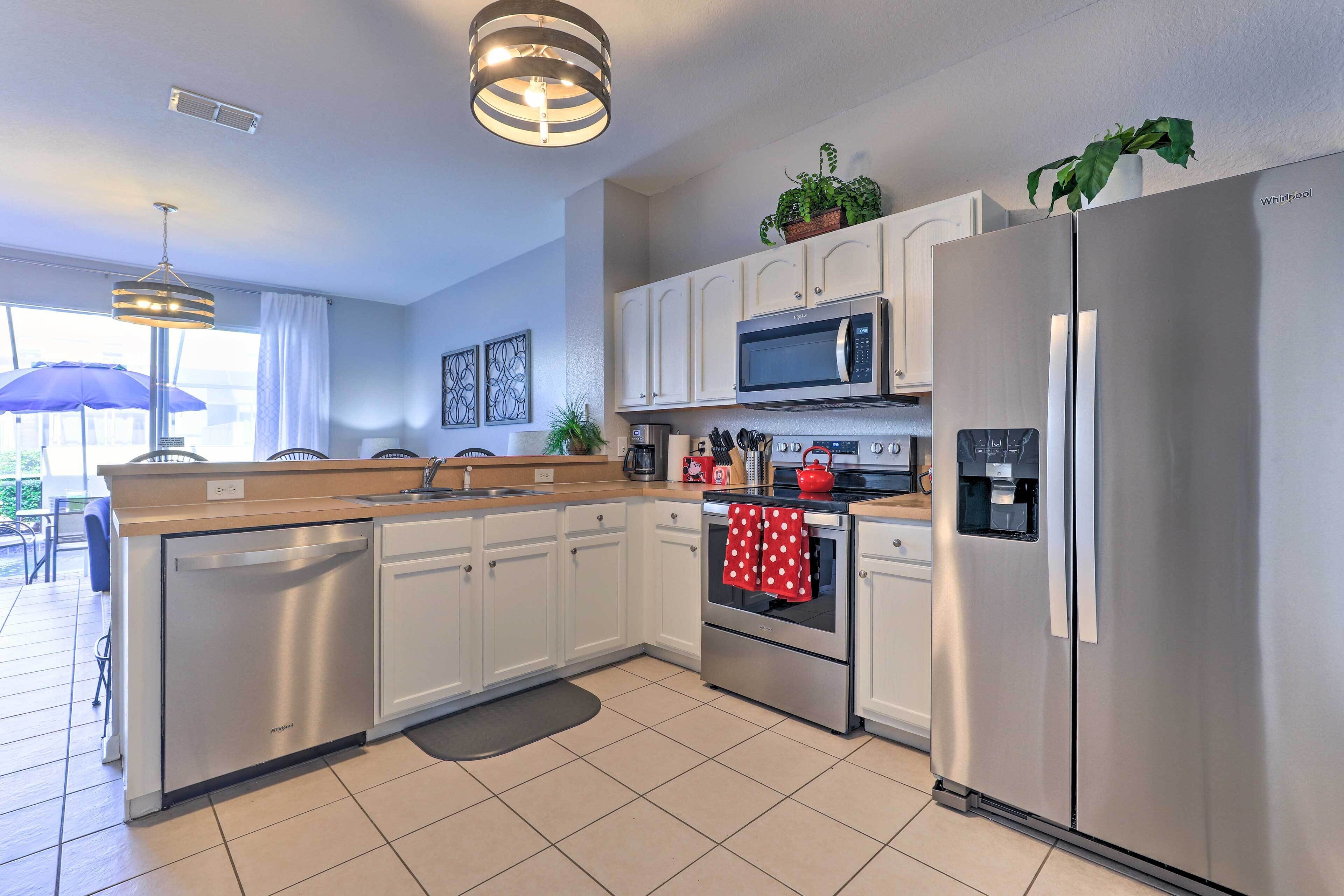 A modern kitchen with stainless steel appliances, white cabinetry, and a central island.