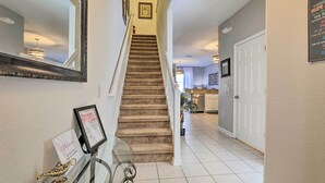 A staircase leading to a second floor, a framed certificate on a glass table, and a door with a sign. - Private Cocktail Pool: Kissimmee Resort Retreat! (Kissimmee)