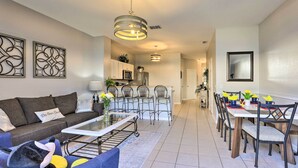 A modern living room with a sofa, coffee table, and a dining area with chairs and a table. - Private Cocktail Pool: Kissimmee Resort Retreat! (Kissimmee)