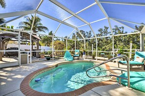 A covered outdoor swimming pool with a brick edge, surrounded by lounge chairs and a barbecue area.