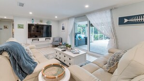 A living room with a sofa, a coffee table, and a TV. There is a window with a view of the outside. - Backyard Oasis! Waterfront Haven in Bradenton (Bradenton)