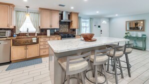 A modern kitchen with a central island, bar stools, and a large window. - Backyard Oasis! Waterfront Haven in Bradenton (Bradenton)