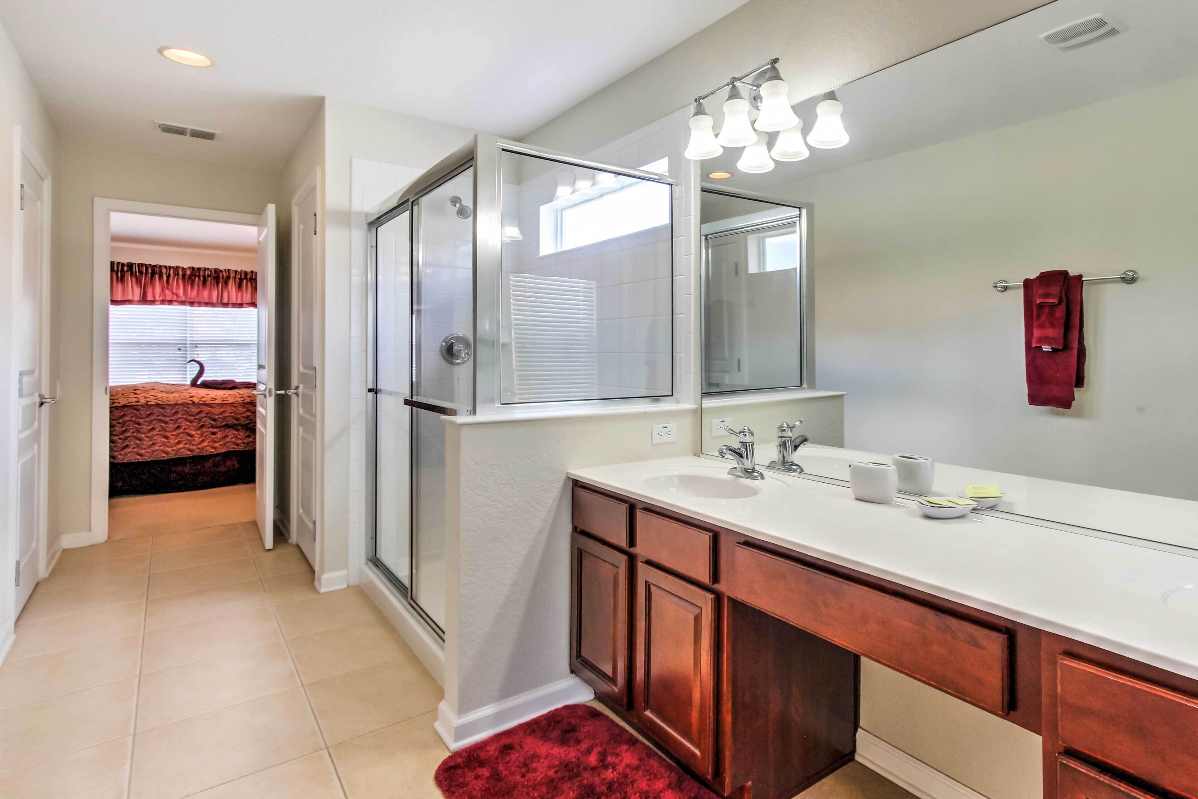 A bathroom with a glass shower enclosure, a white sink, and a large mirror.