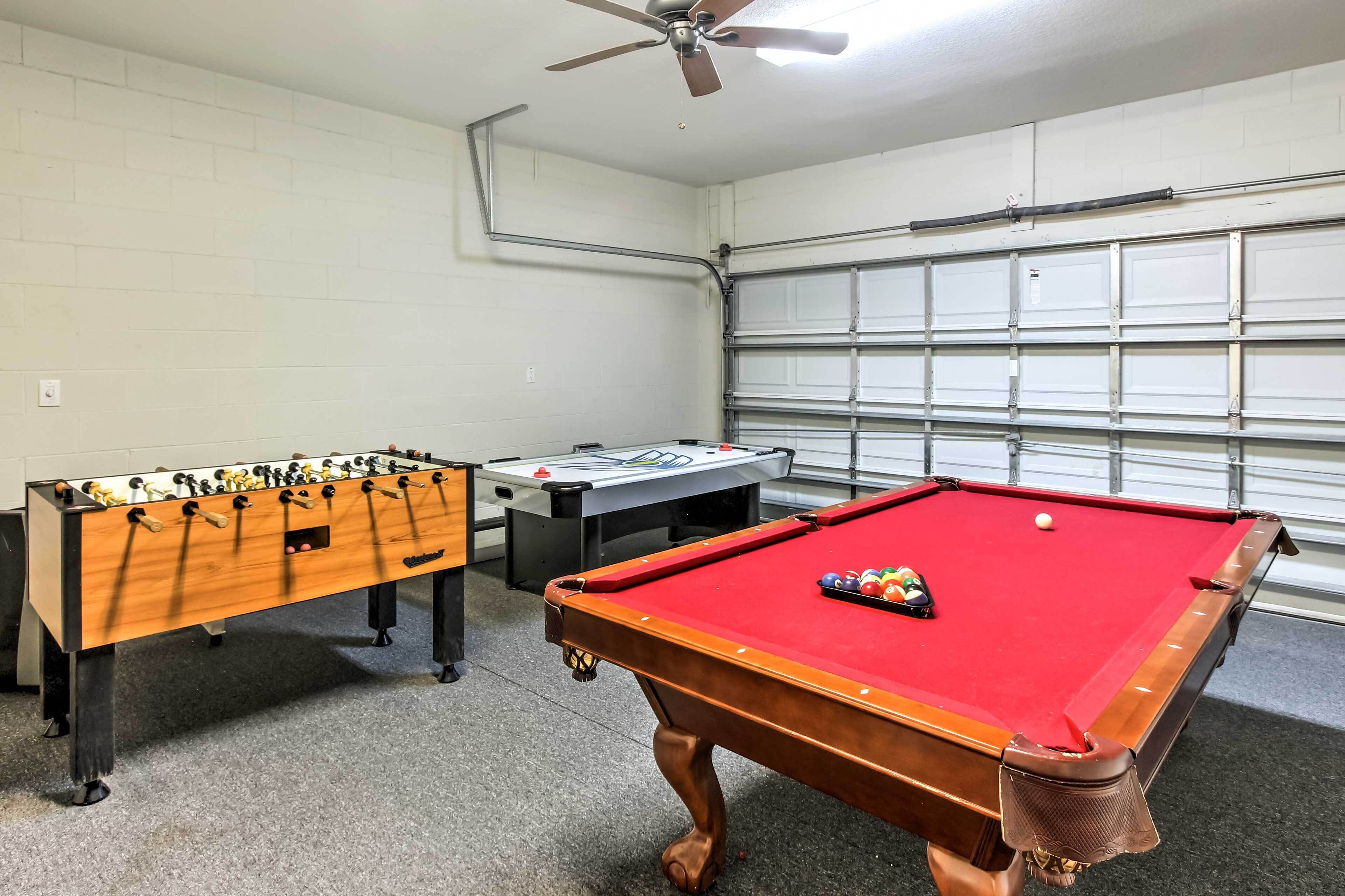 A room with a pool table, a foosball table, and a ping pong table.