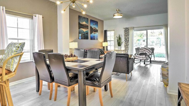 A modern dining area with a glass-top table, black chairs, and a chandelier. - Fire Pit + Pool Access: Resort Getaway Near Disney (Kissimmee)