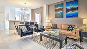 A modern living room with a sofa, chairs, a coffee table, and artwork on the wall. - Fire Pit + Pool Access: Resort Getaway Near Disney (Kissimmee)