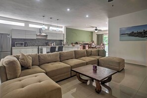 Una sala de estar moderna con un sofá modular, una mesa de centro y un comedor con mesa y sillas.